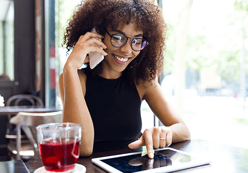 Woman speaking on phone and taking notes – Reverse Phone Append services for updating customer contact data