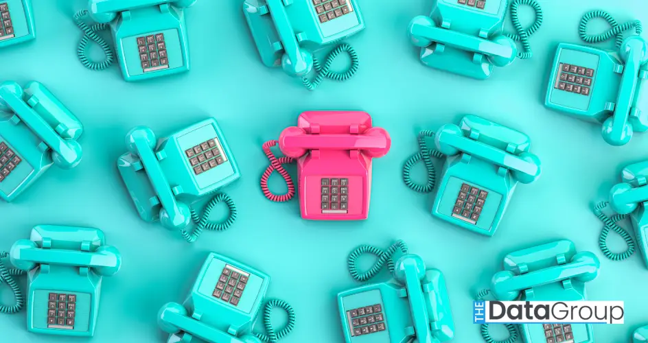 Overhead view of retro telephones in turquoise, with one pink phone centered among them for contrast.