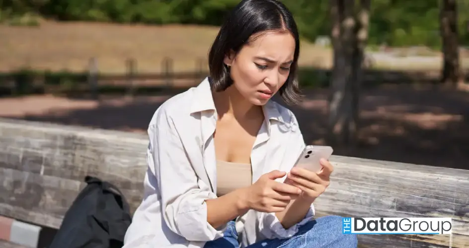 asian girl frowning looking concerned her mobile phone reading sad message bad news smartphone 1