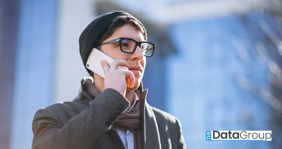 Business man by the skyscraper using phone